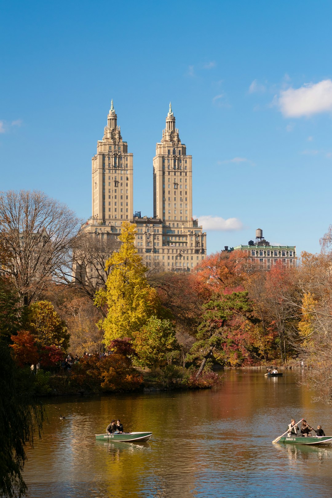 Boats on a lake with autumn trees and Manhattan buildings beyond
