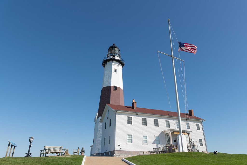 Montauk Point Lighthouse, its lawn and a flagpole under a blue sky