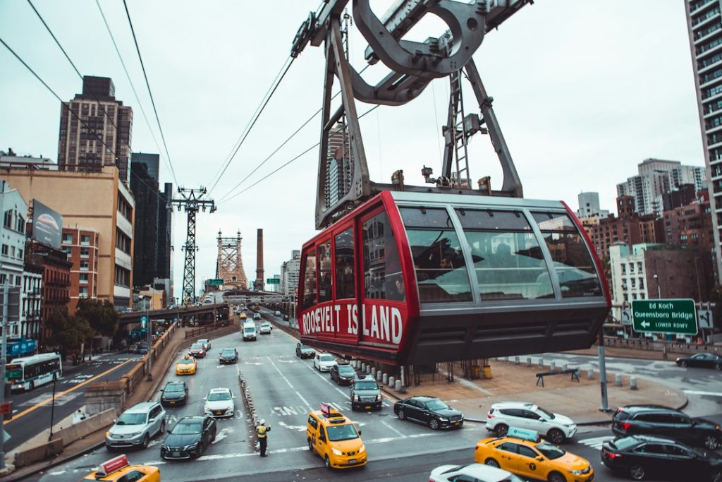 A red Roosevelt Island tram cabin above a Manhattan street
