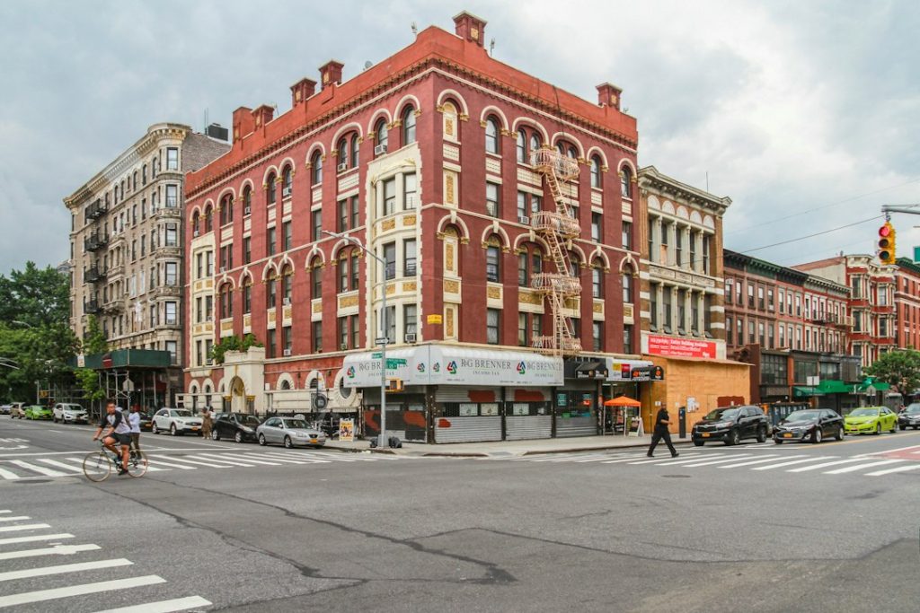 A Harlem street corner lined with brick buildings and shops