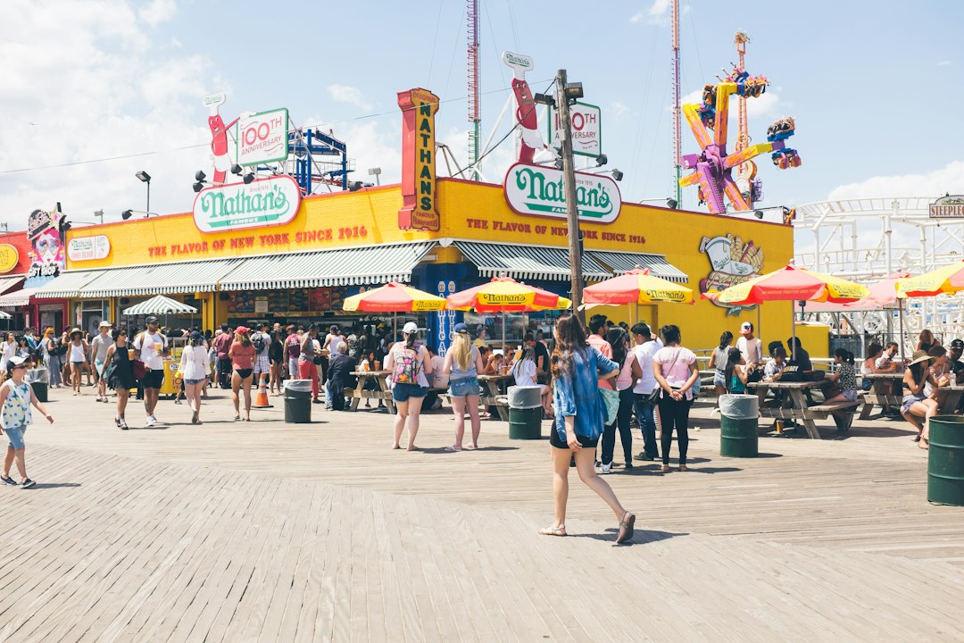 Visitors outside colorful food and amusement storefronts at Coney Island