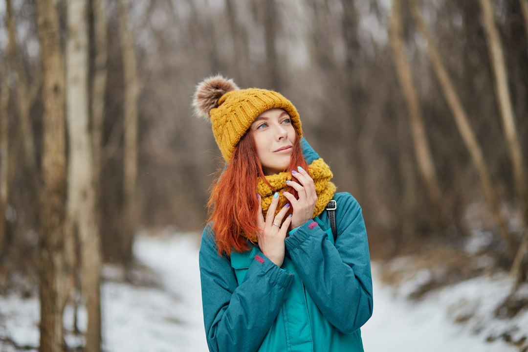 Woman in a teal winter coat and mustard hat on a snowy woodland walk; lifestyle inspiration