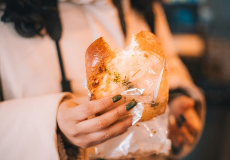 A person holding a pastry during a food stop on Roosevelt Avenue in Queens