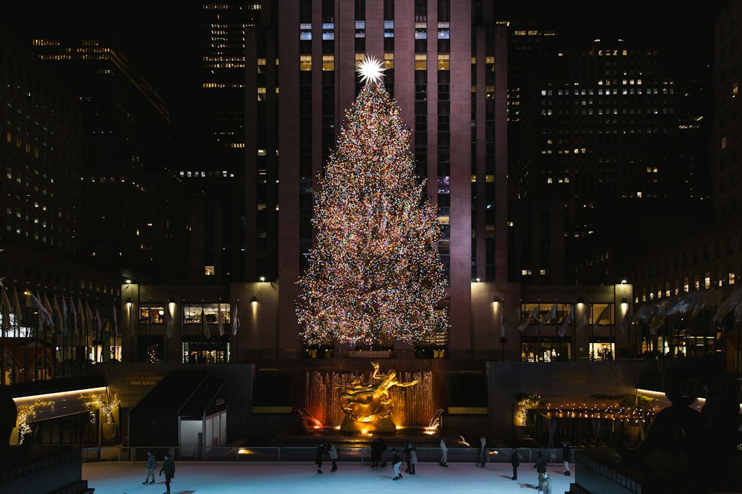 A Christmas tree lit in a New York City plaza at night