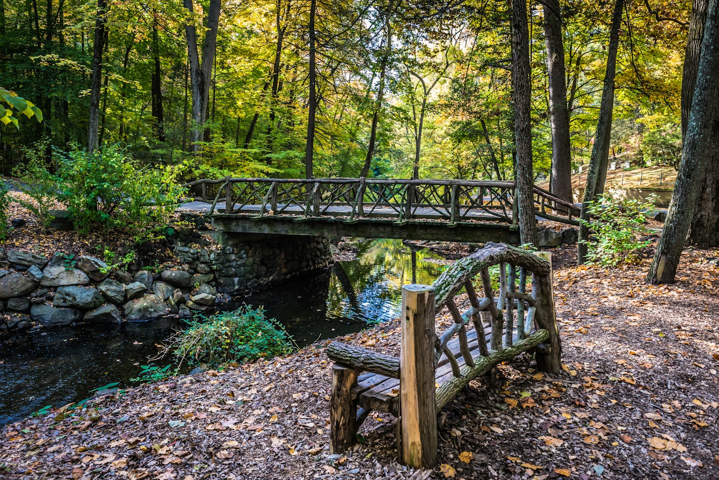 A rustic footbridge and bench in the wooded grounds of Sleepy Hollow Cemetery
