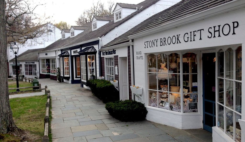 A paved walkway beside white shopfronts at Stony Brook Village Center