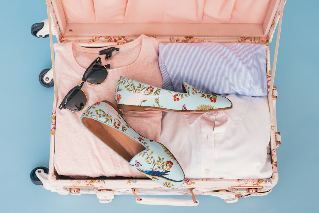 An open pink suitcase with carefully packed clothes and shoes