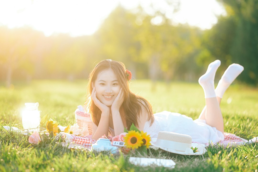 A smiling woman relaxing on a picnic blanket in a sunlit park