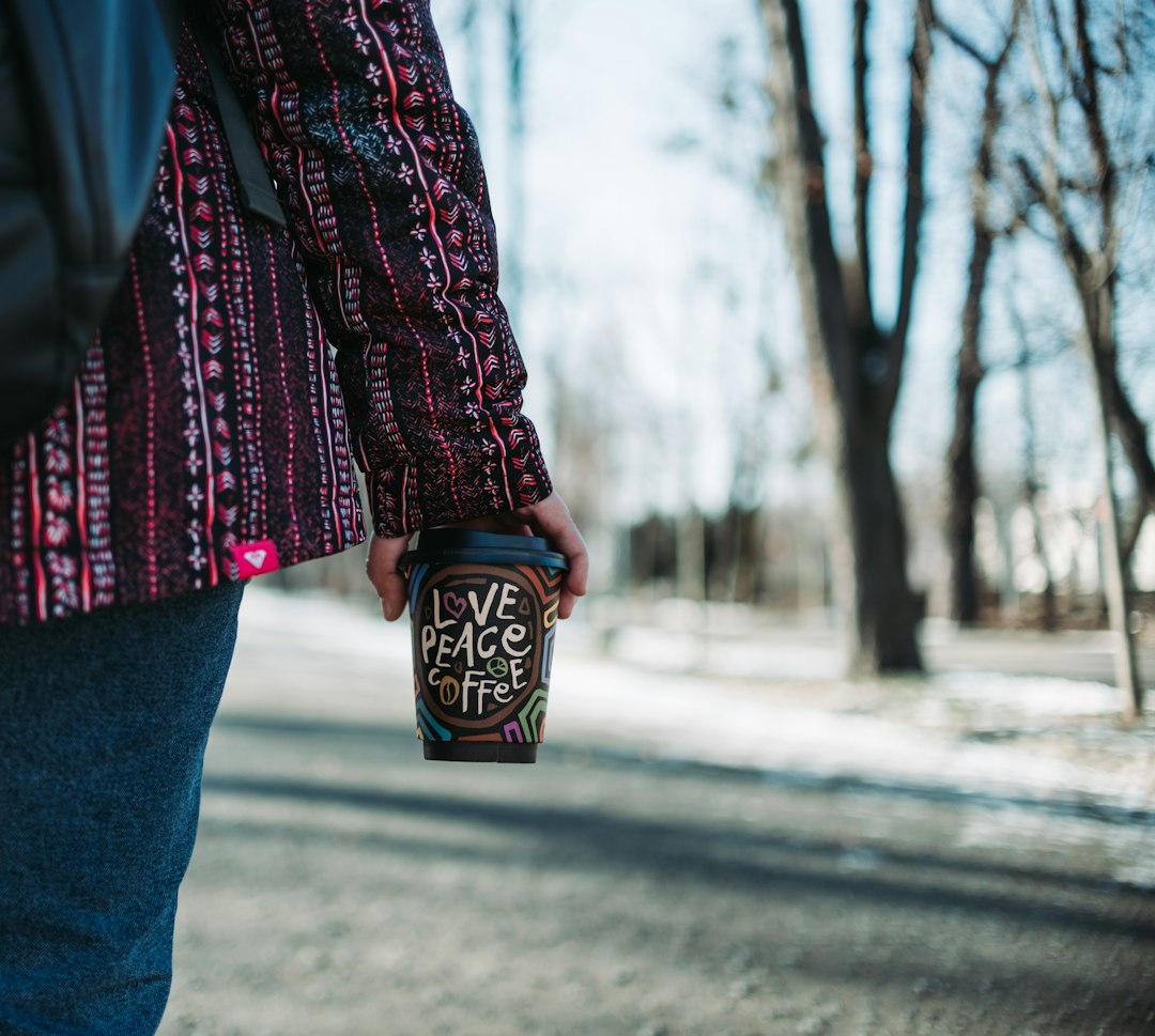A reusable travel cup held during an outdoor walk