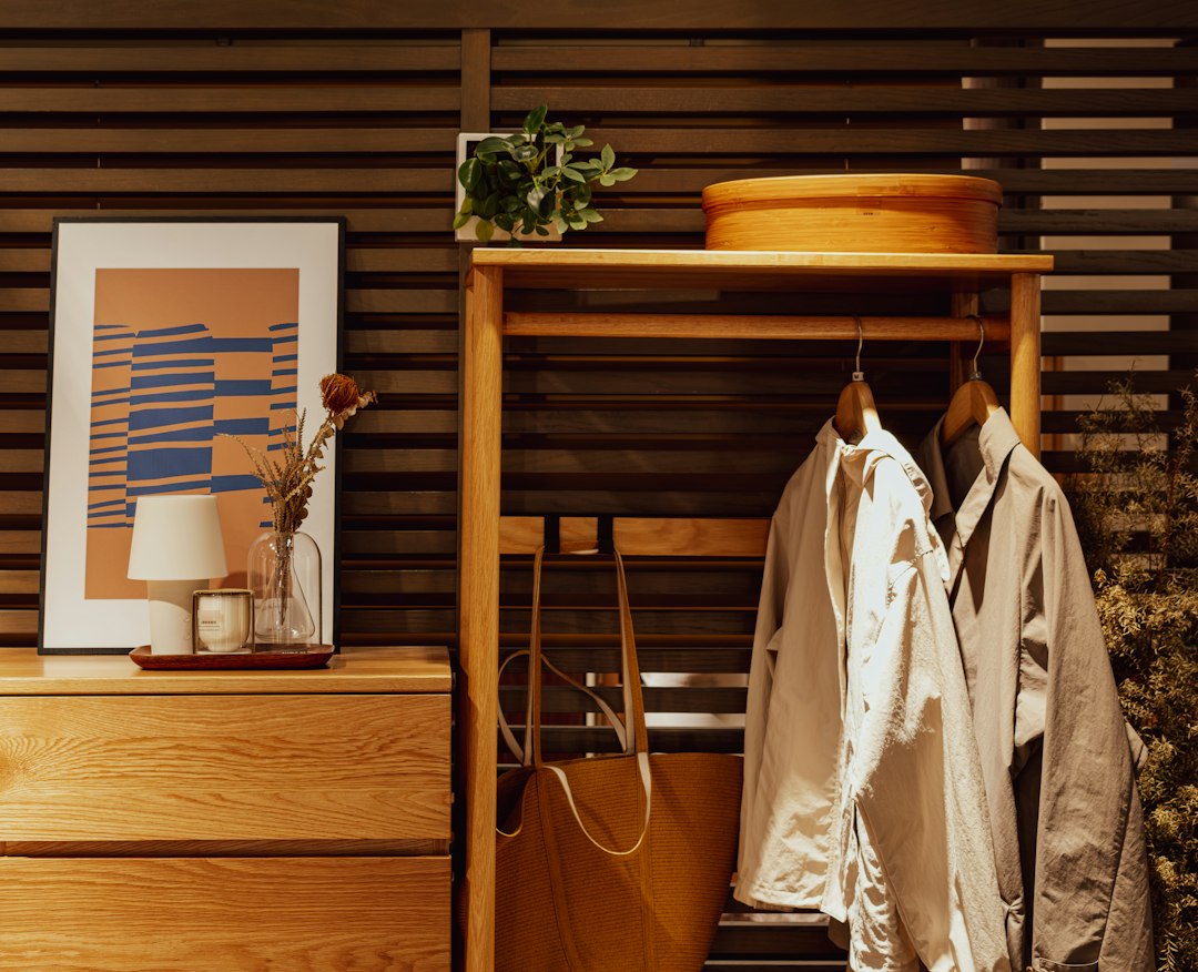 Coats hanging beside a wooden cabinet in a tidy home entry