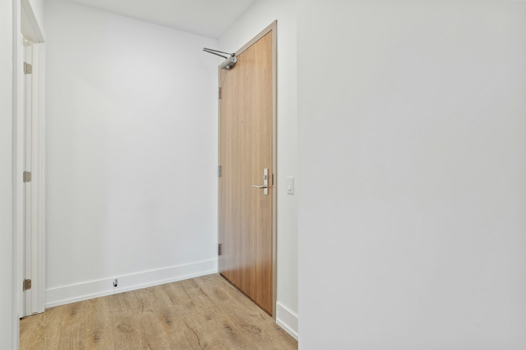 A clear, narrow entryway with white walls and a wooden door