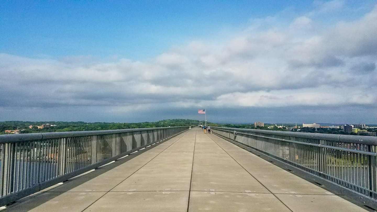 The pedestrian deck of Walkway Over the Hudson with an American flag above the river