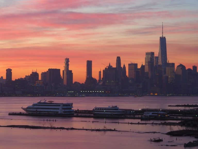 Passenger boat on New York waters beneath a pink skyline